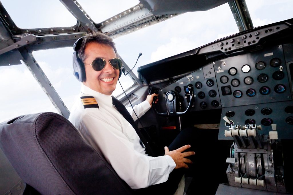 male pilot sitting in plane smiling