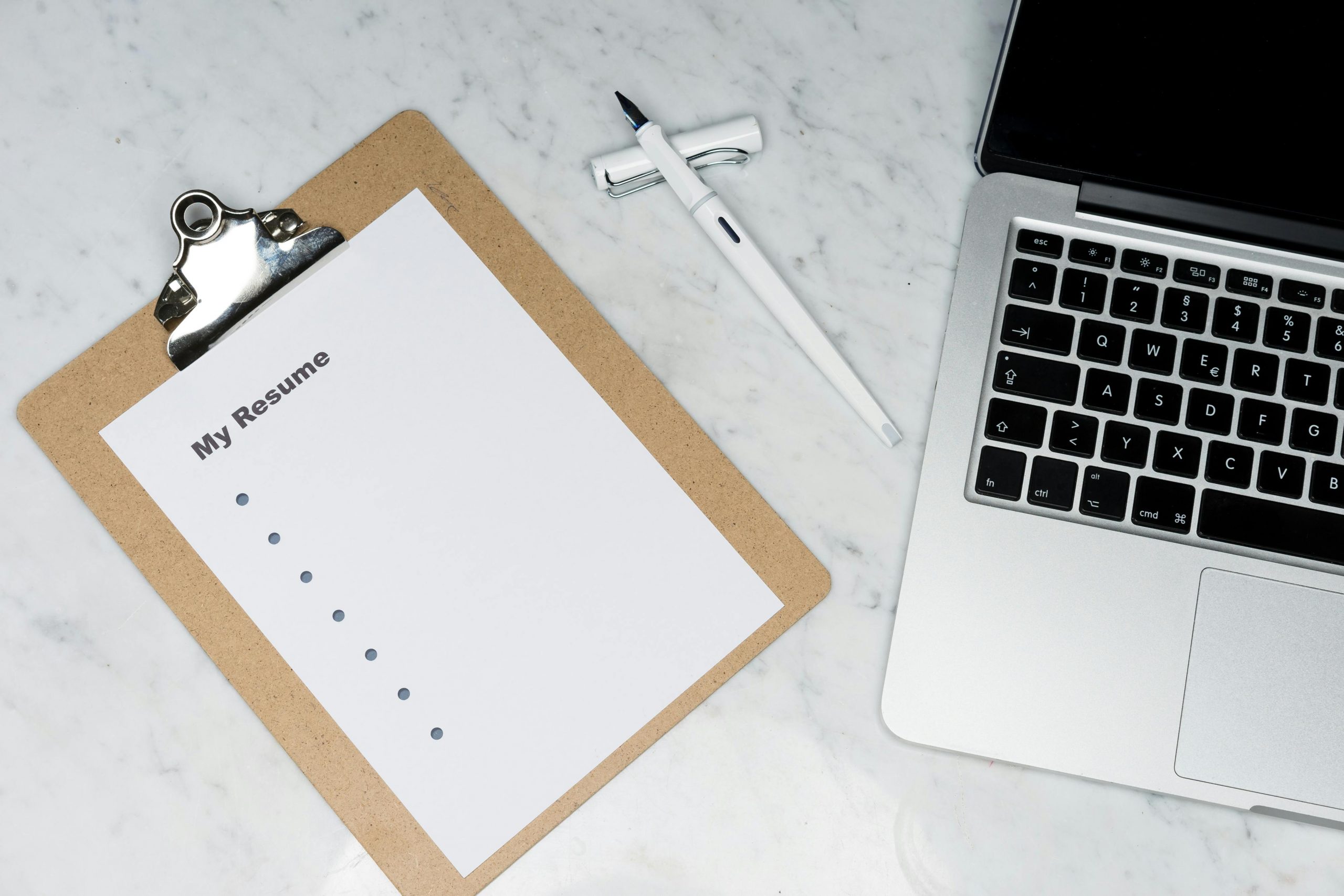 resume template, pen, and laptop on a marble surface